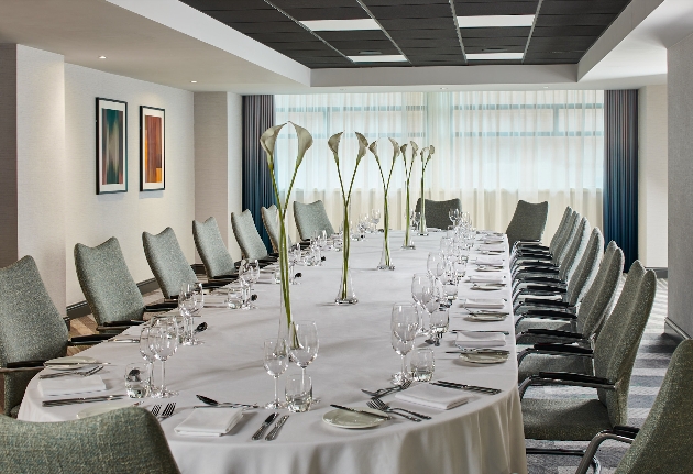 A long white table surrounded by chairs in a modern-looking room