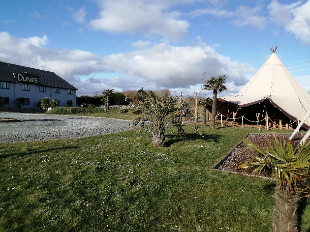 Grass with a tipi on the right and a building on the left