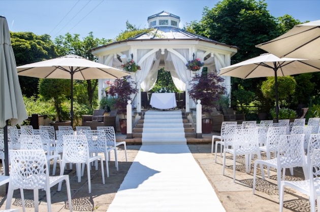 A white gazebo surrounded by chairs and a white carpet