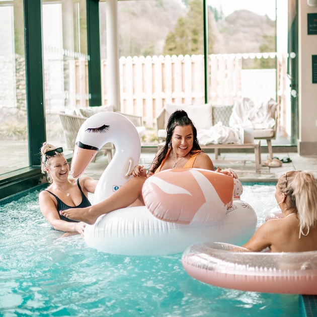 Three women in a swimming pool. two are sitting in rubber rings