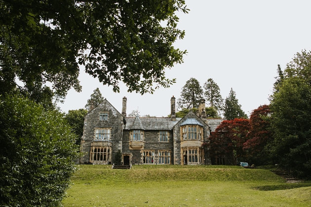 The exterior of a manor house surrounded by trees and grass