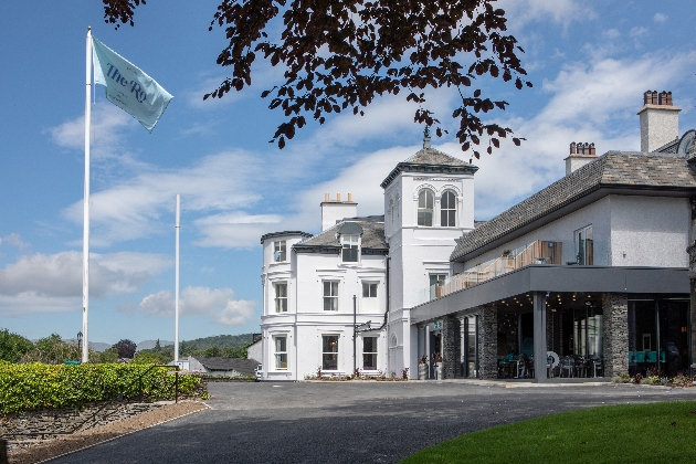 The exterior of a large white building with green hills in the distance