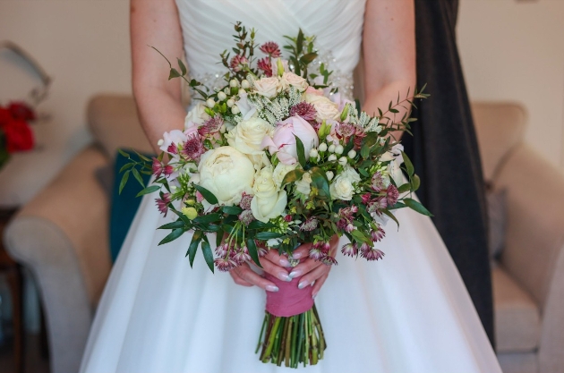 A woman holding a white, pink and green bouquet