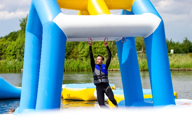 A man hanging from two ropes on an inflatable water course