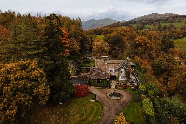 A sky view of a large manor house surrounded by trees