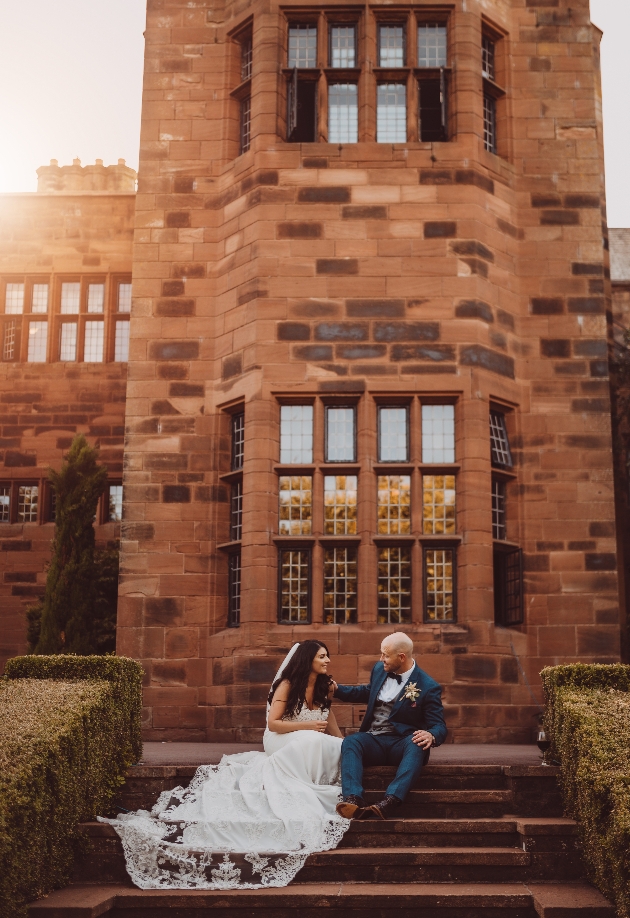 A bride and groom sitting in front of a large brick building