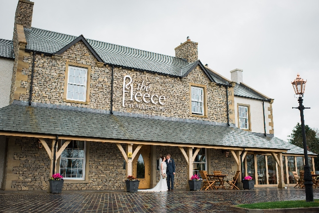 A bride and groom standing outside of a brick building