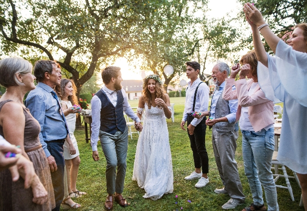 Bride and groom exiting their outdoor ceremony in hail of confetti