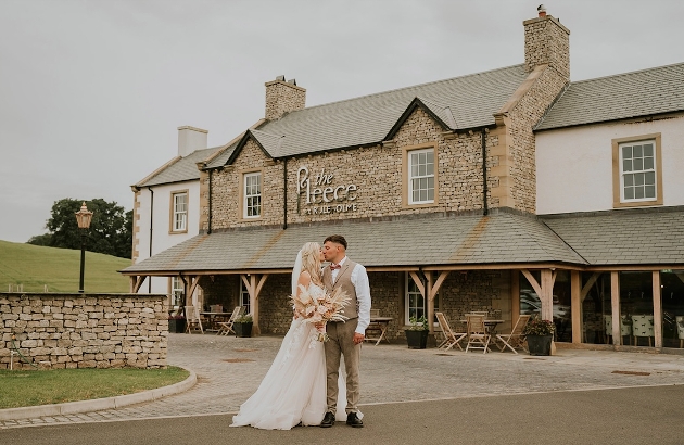 A bride ad groom kissing in front of a brick building