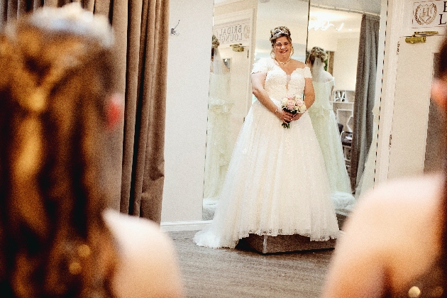 A bride in a wedding dress standing in a dressing room