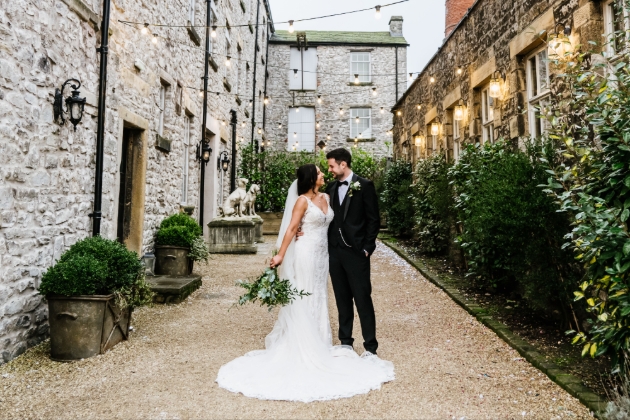 A bride and groom smiling at each other in a courtyard