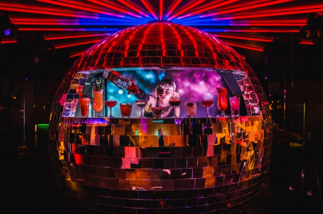 A woman serving drinks out of a disco ball-shaped bar