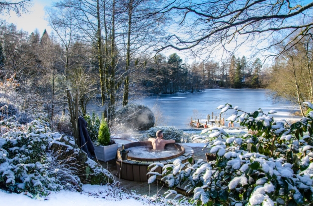 A man in a hot tub overlooking a lake